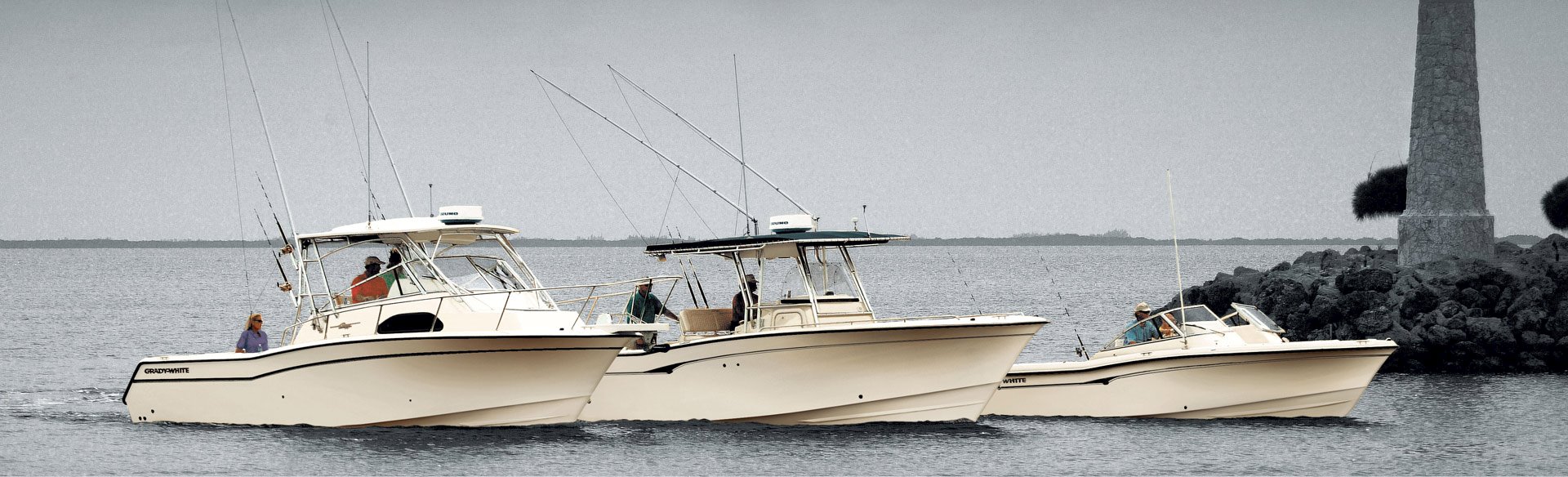 Three Grady-White boats motor together with rods ready to fish.