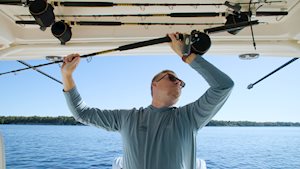 Person storing fishing rods in the hardtop rod storage on a Grady-White Freedom 345 dual console boat