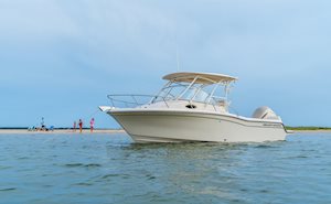 Grady-White's Adventure 218 21-foot walkaround cabin boat anchored near shore as a family plays on the beach