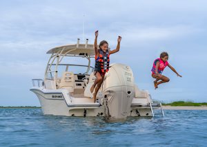 Grady-White's Adventure 218 21-foot walkaround cabin boat anchored near shore as girls jump from stern