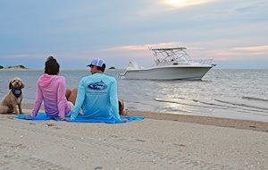 Grady-White's Adventure 218 21-foot walkaround cabin boat with couple and dog relaxing on the beach