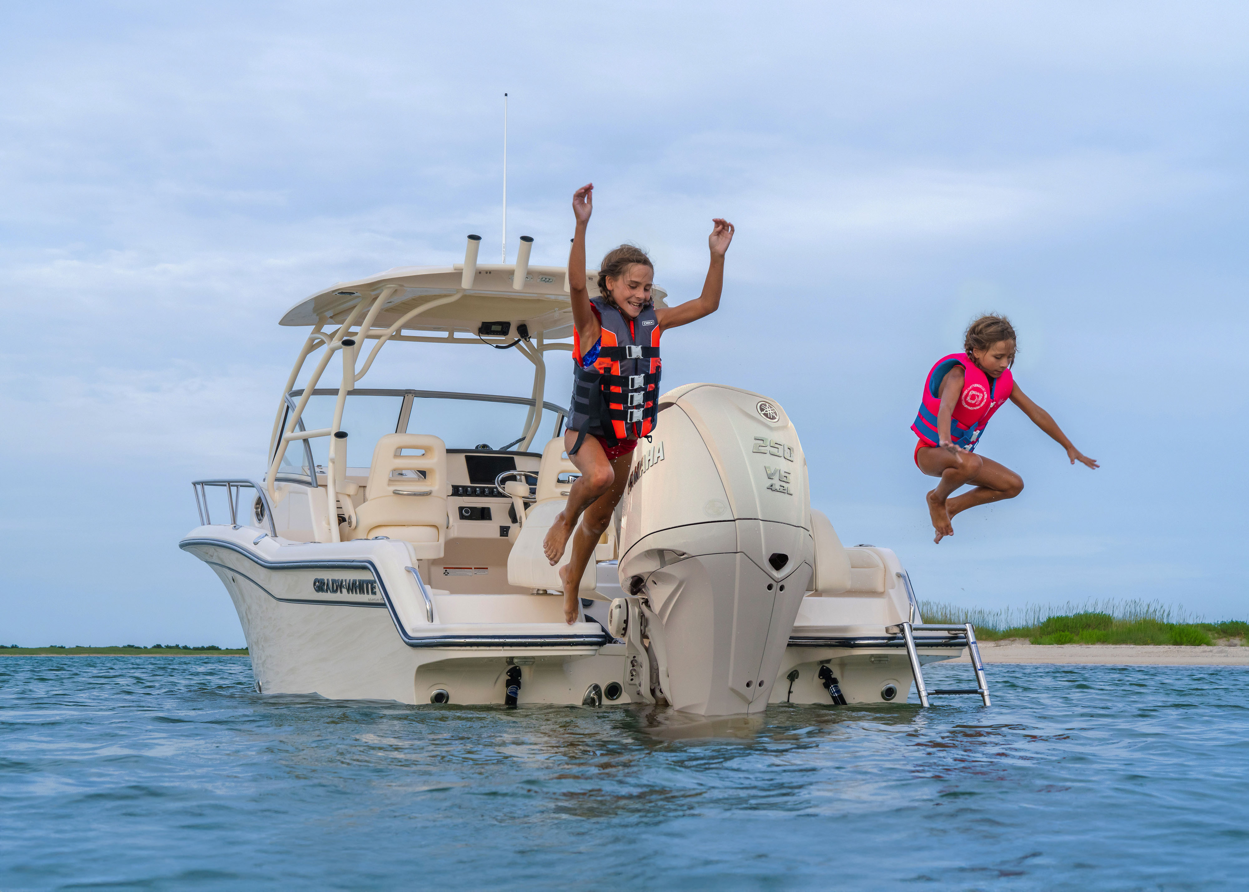 Two children jumping off a Grady-White Adventure 218 21 foot Walkaround Cabin Boat.