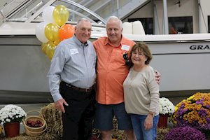 Three people posing in front of a Grady-White boat