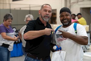 Two men smiling and pointing at each other